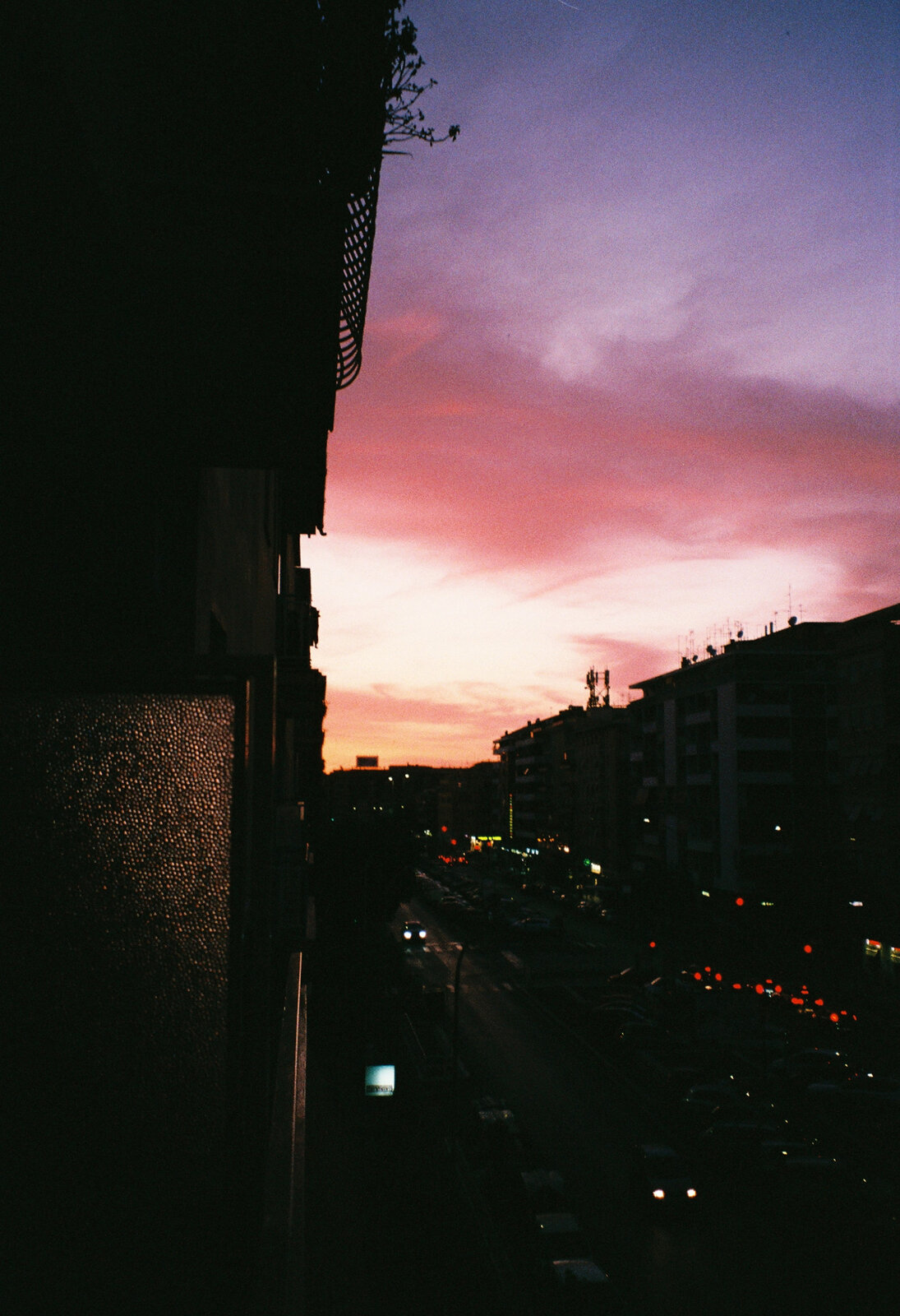 A vivid magenta sunset over city rooftops